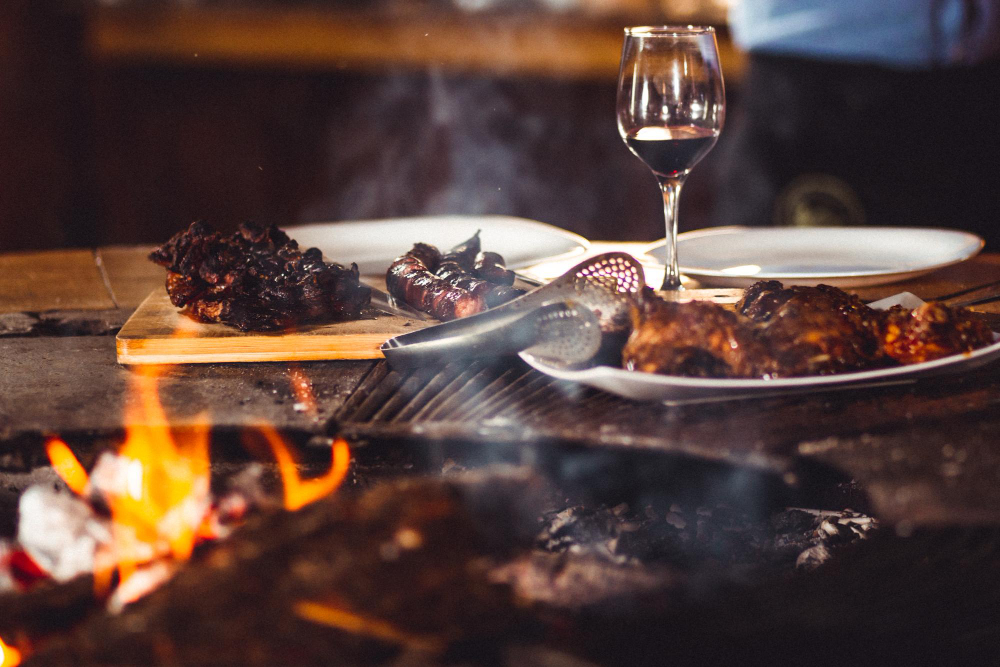 closeup-shot-barbequed-meat-glass-wine-near-fireplace